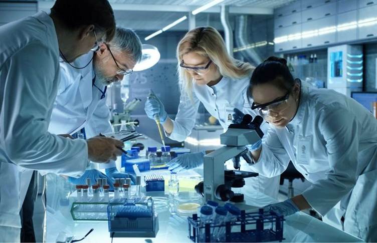 This may contain: three people in white lab coats looking through microscopes