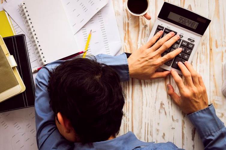 This may contain: a man sitting at a desk working on a calculator